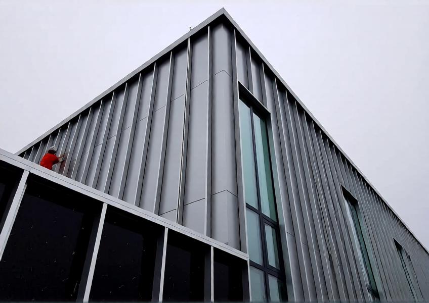 Detailed view of an aluminum cladding curtain wall system during installation, highlighting technical performance features such as insulation, drainage, and modular assembly.