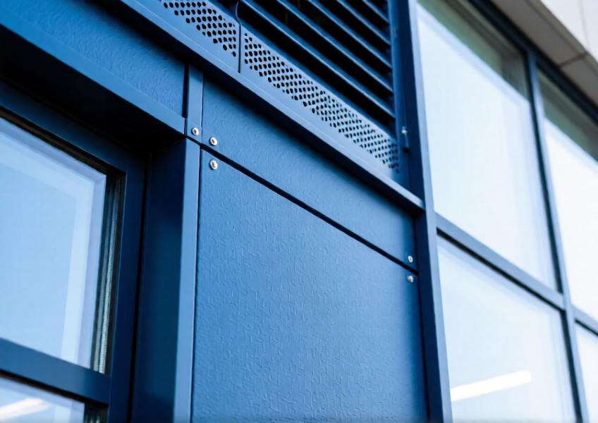 Detailed view of deep blue powder-coated aluminum wall panel within a curtain wall, showcasing finish and integration.
